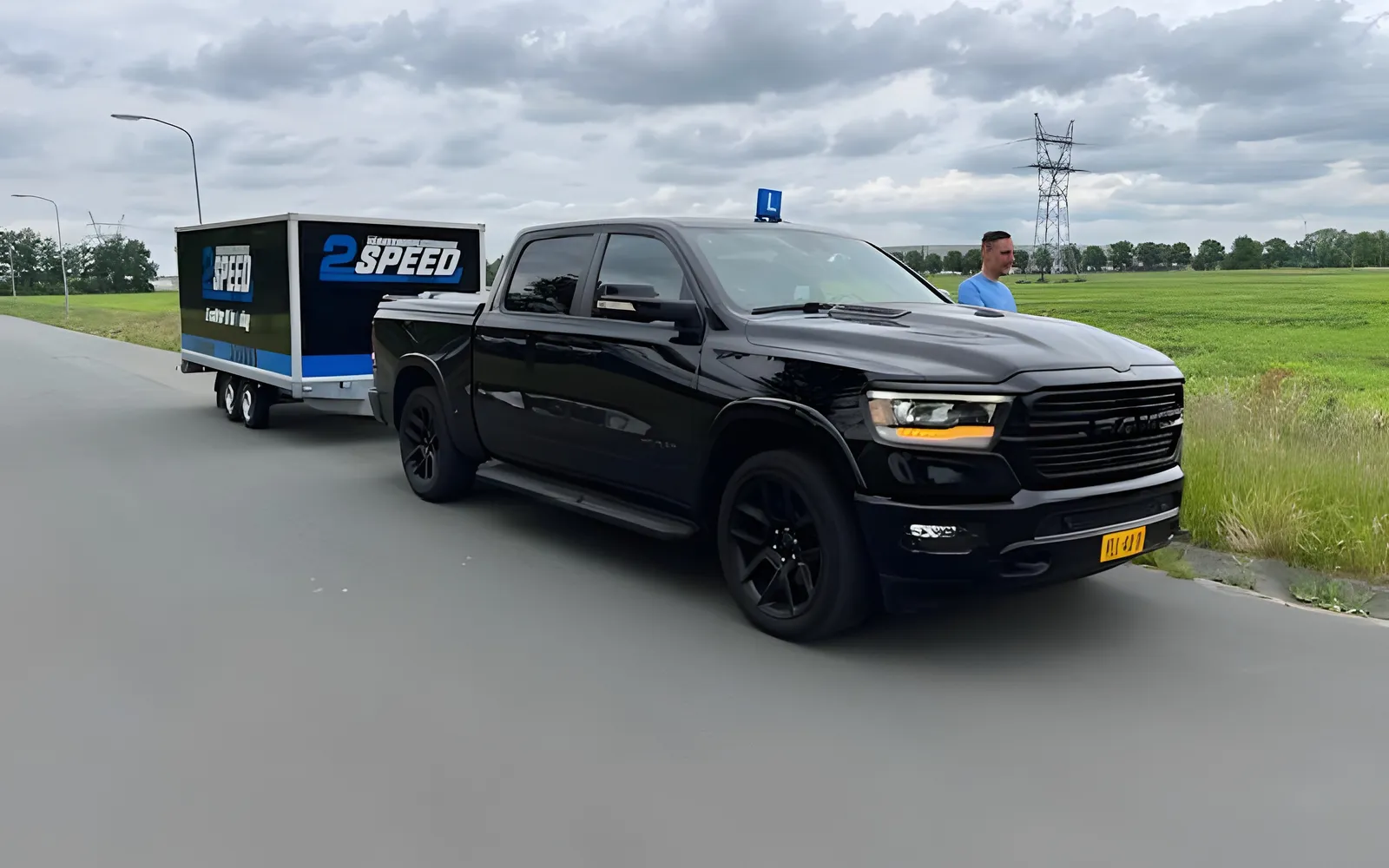 De zwarte Dodge RAM van 2Speed met de 2SPEED-aanhanger langs een polderweg