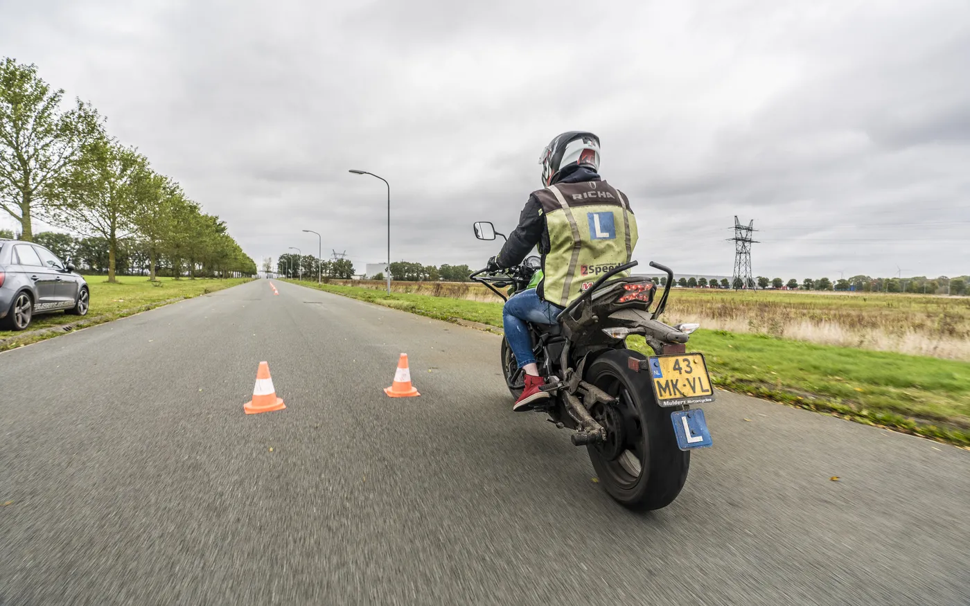 Een leerling op een groene Kawasaki-lesmotor van 2Speed tussen de pionnen