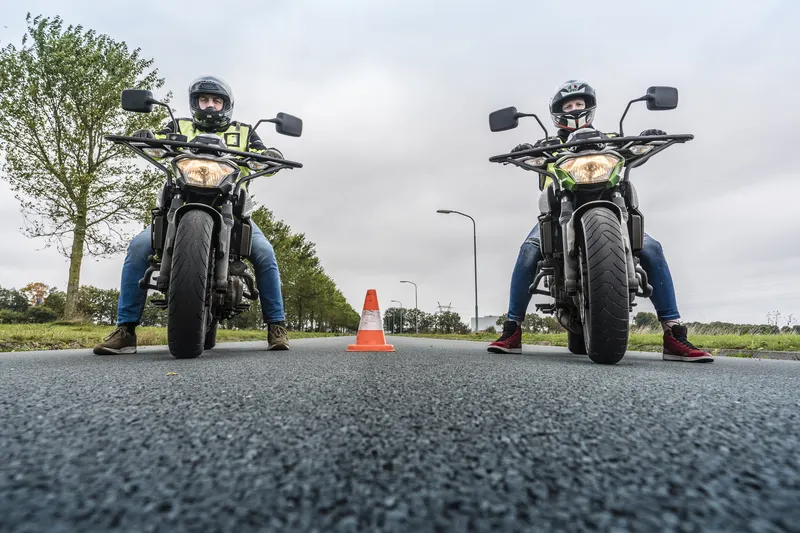 Twee leerlingen op Kawasaki-lesmotoren van 2Speed bij de pionnen